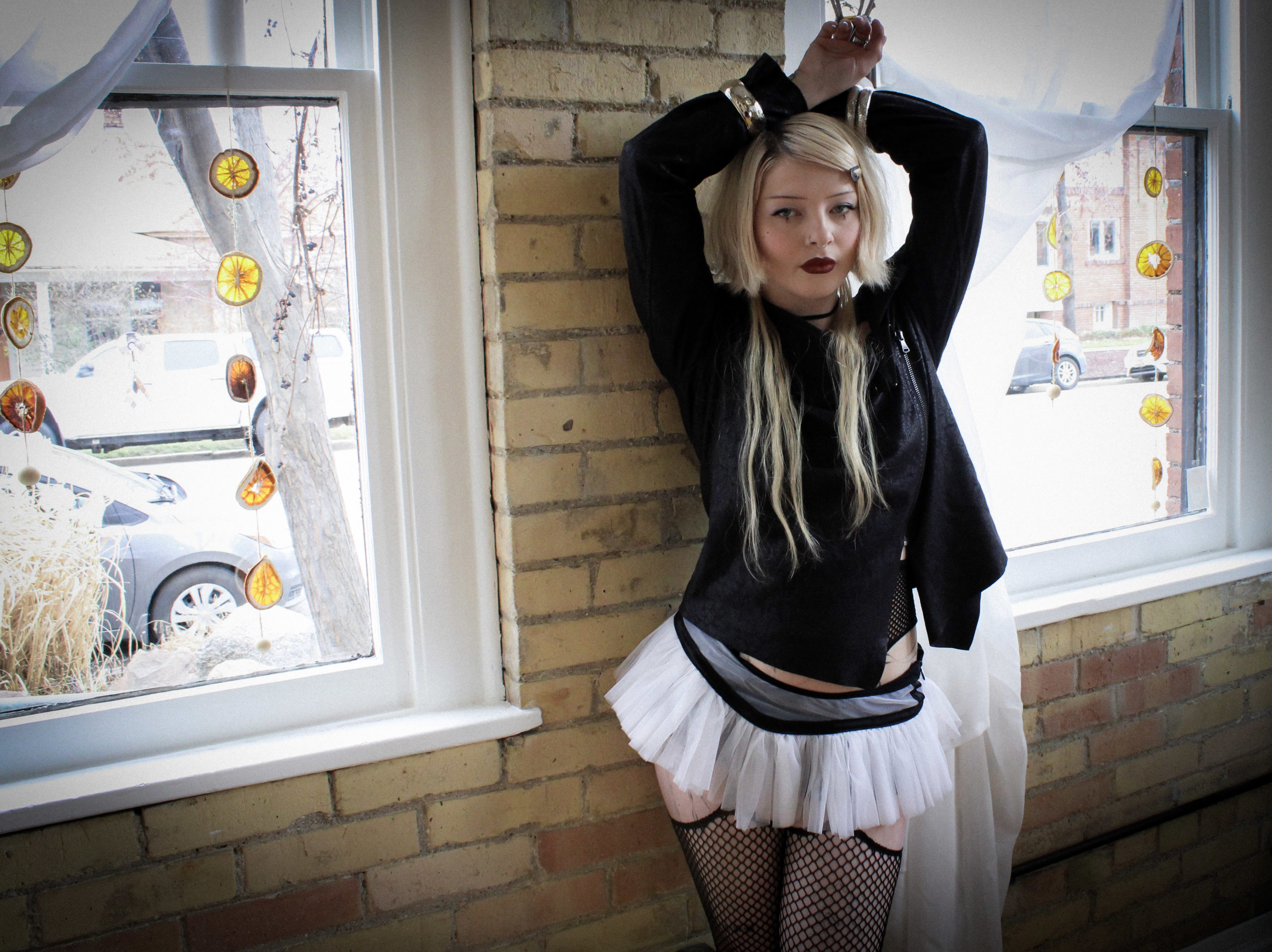 Kate Johnson standing against a wall with windows and her hands in the air