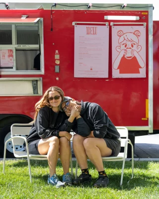 The owners of Girls Who Smash sit together in front of the food truck
