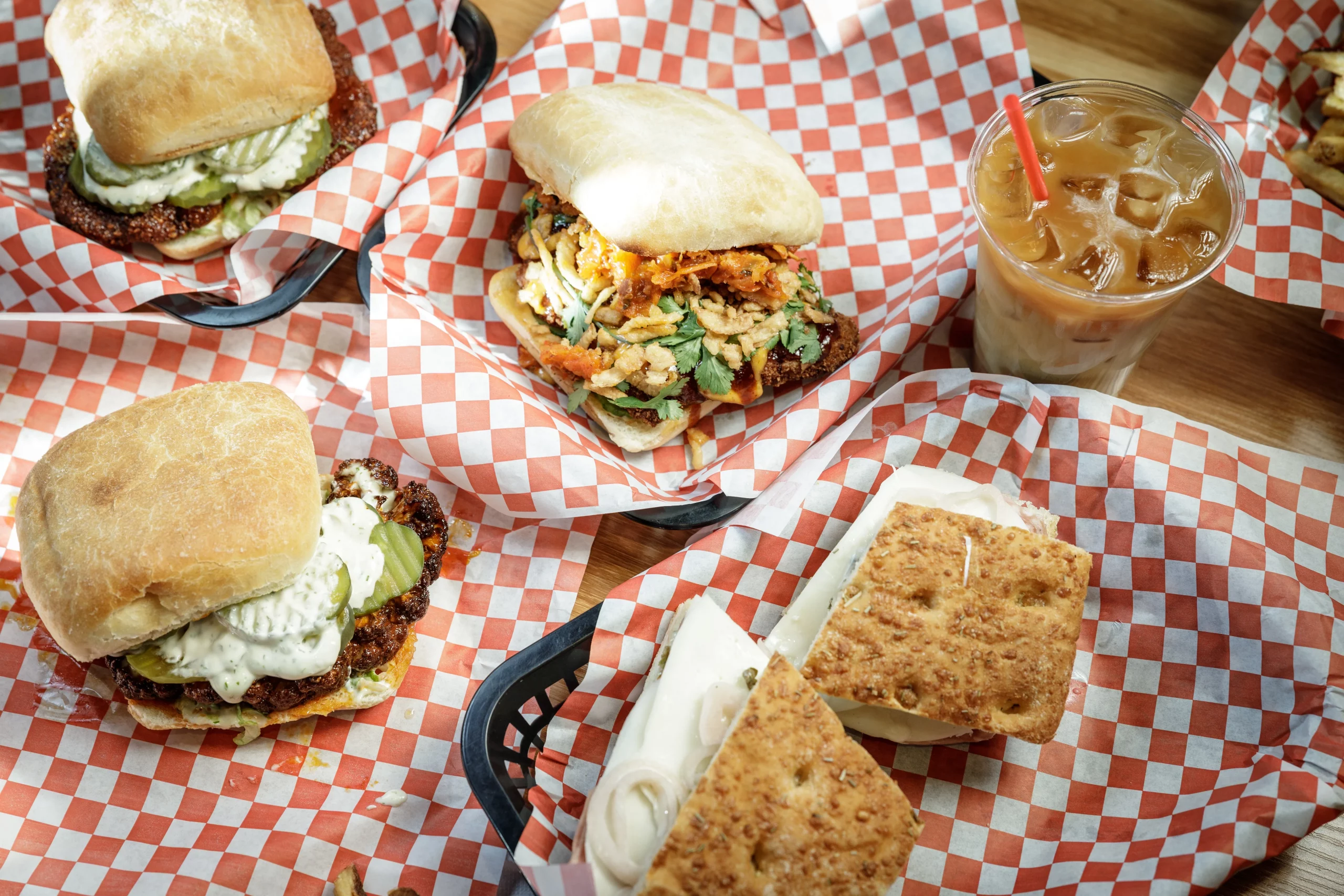 A selection of sandwiches spread across a table, all sitting on red and white checkered papers