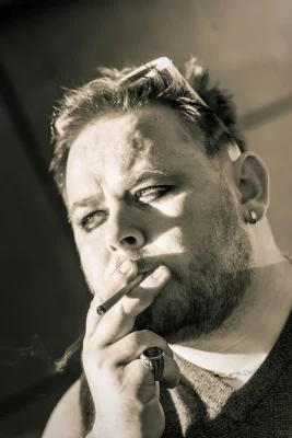 An black-and-white photo of a man smoking a cigarette.