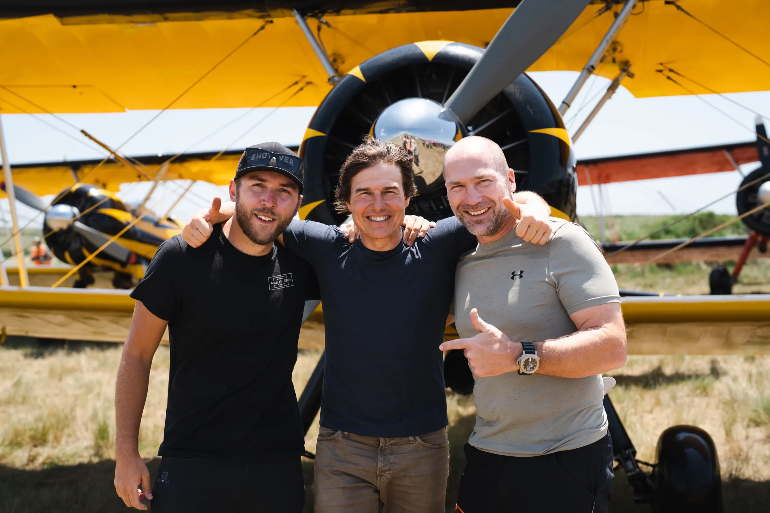 Tree guys standing in front of a prop plane.