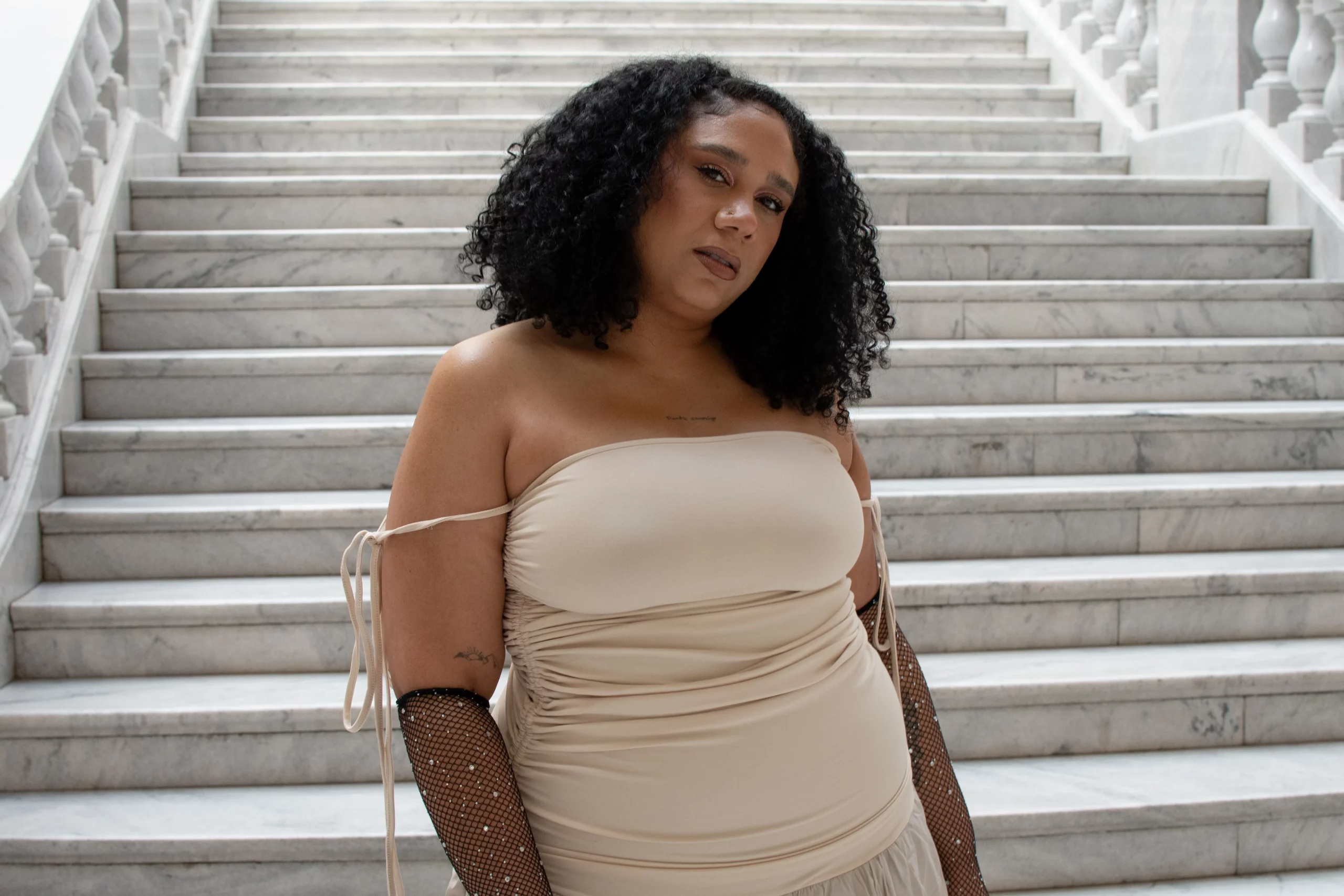 Jazzy Olivo in a cream colored dress standing in front of some steps.