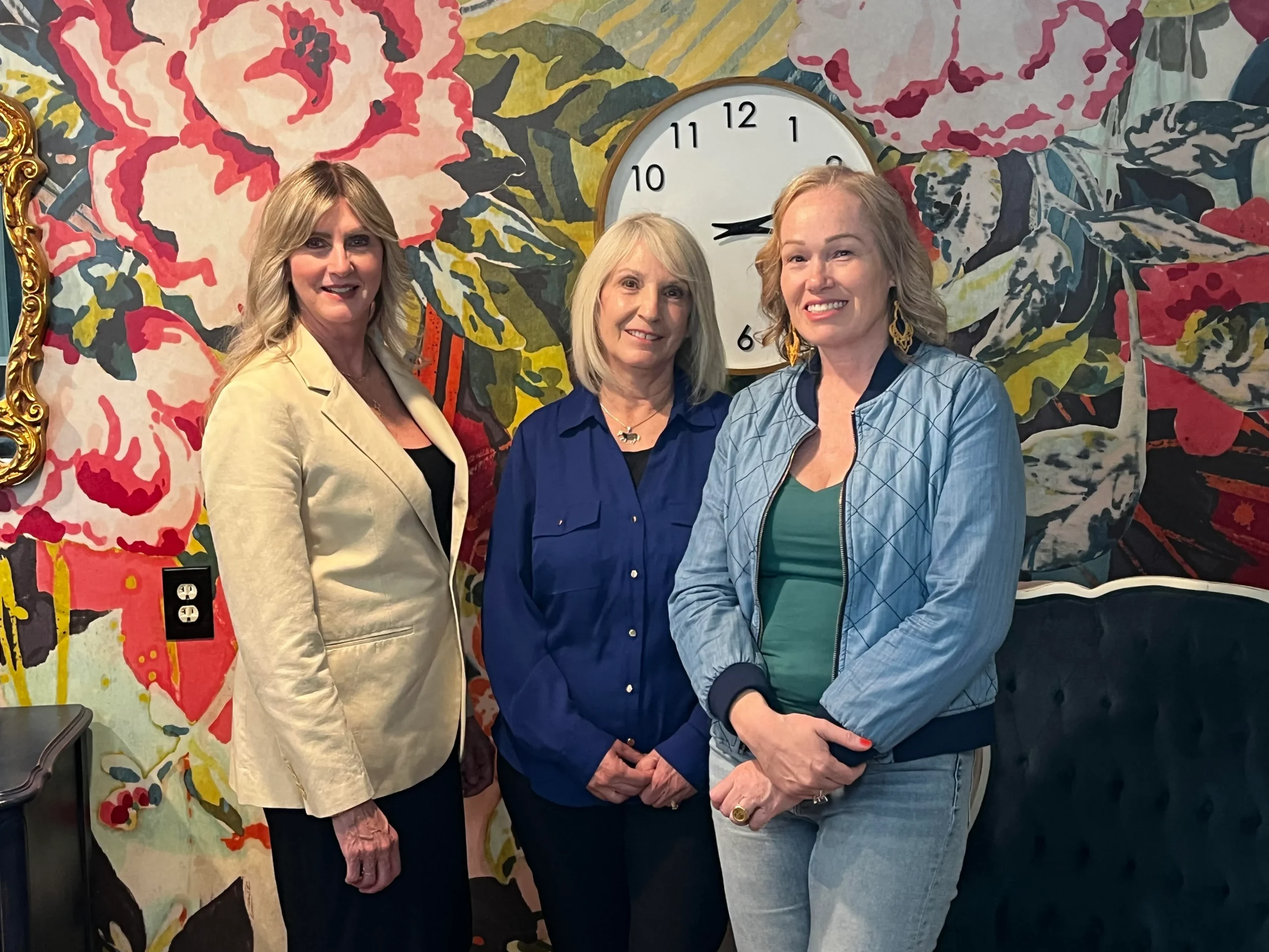 beauty industry professionals pose in front of a floral wall